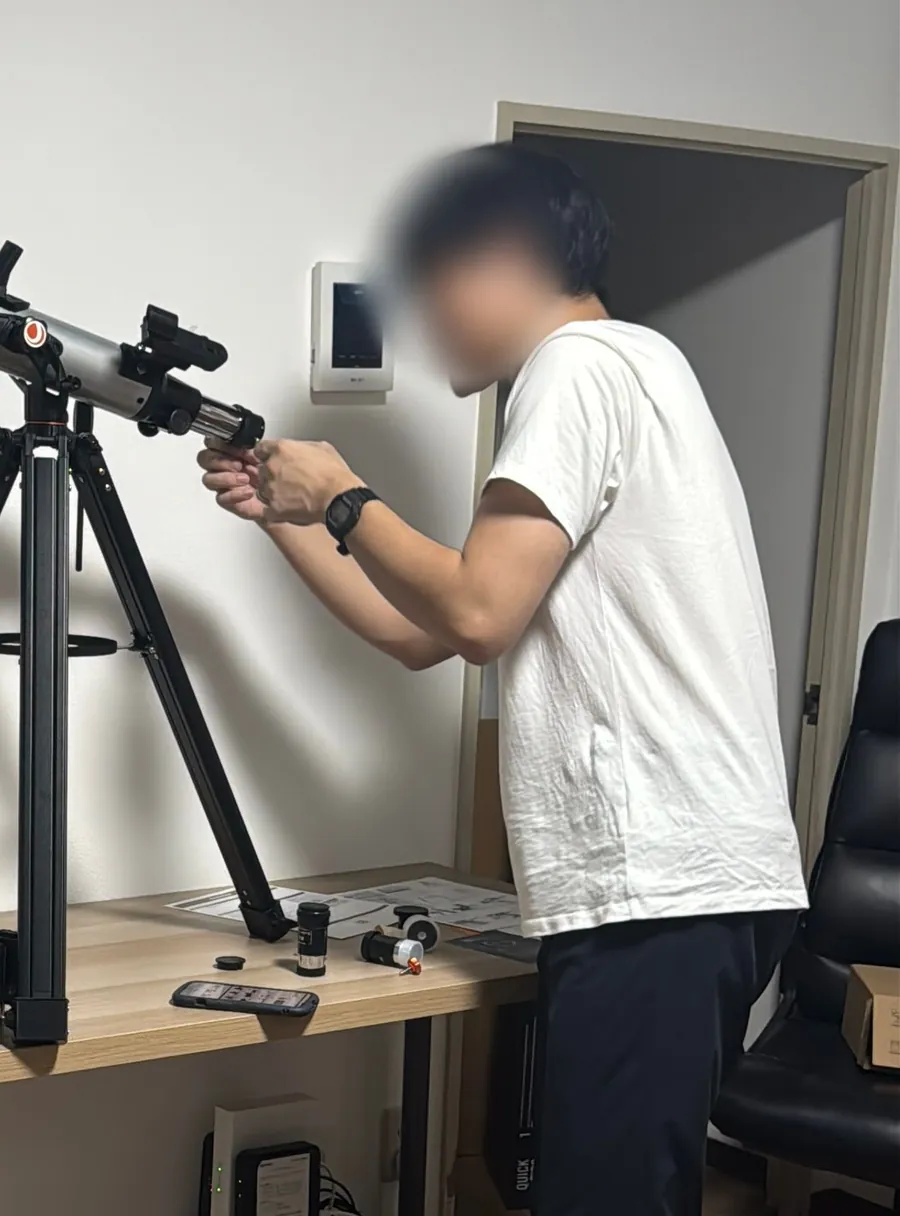 室内で、三脚にのせた鏡筒に部品を取り付けている編集部メンバー(顔はぼかしています)