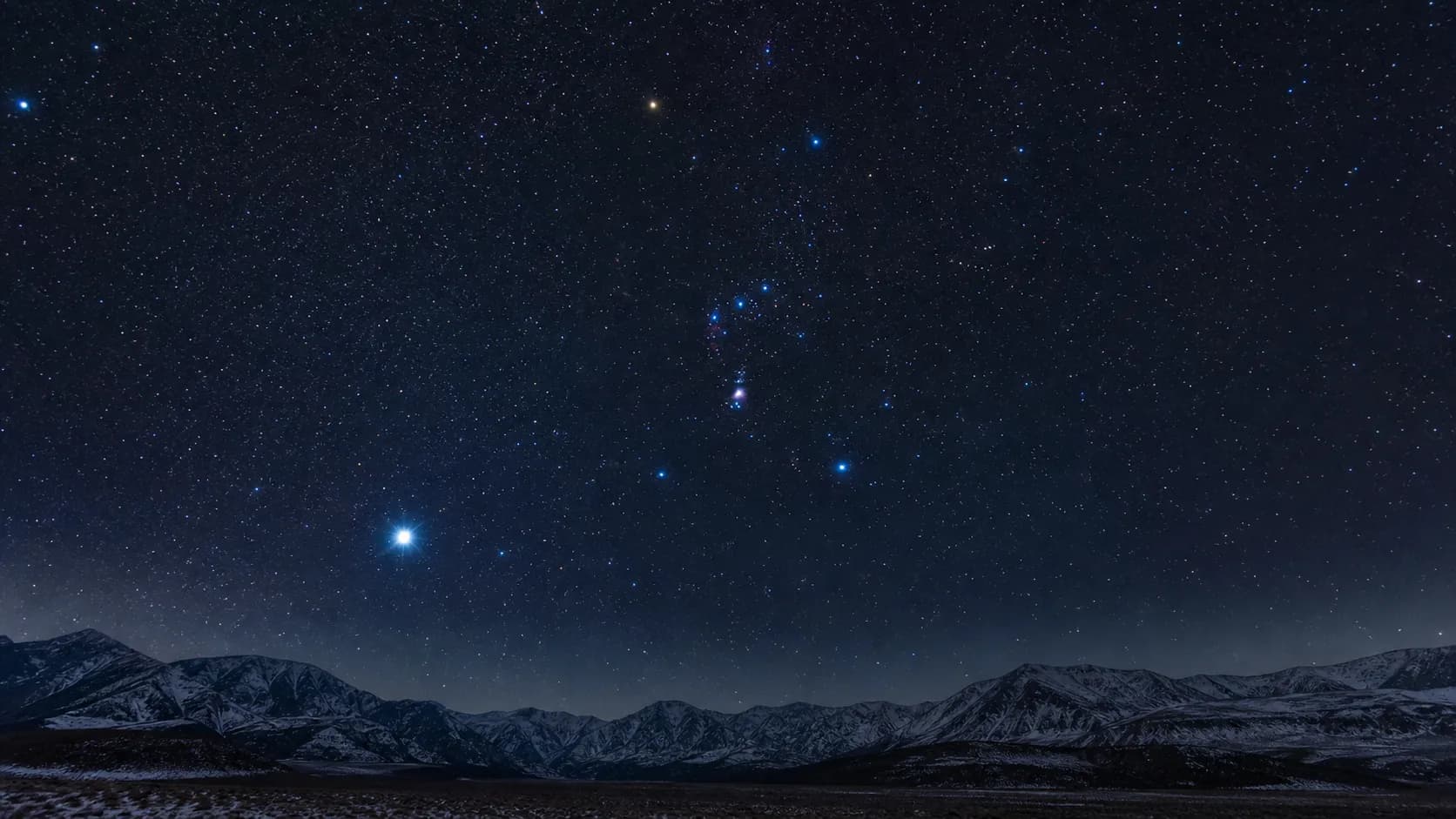 冬の南の空に輝くオリオン座と、その左下で青白く光るシリウス。三つ星がはっきり並ぶ