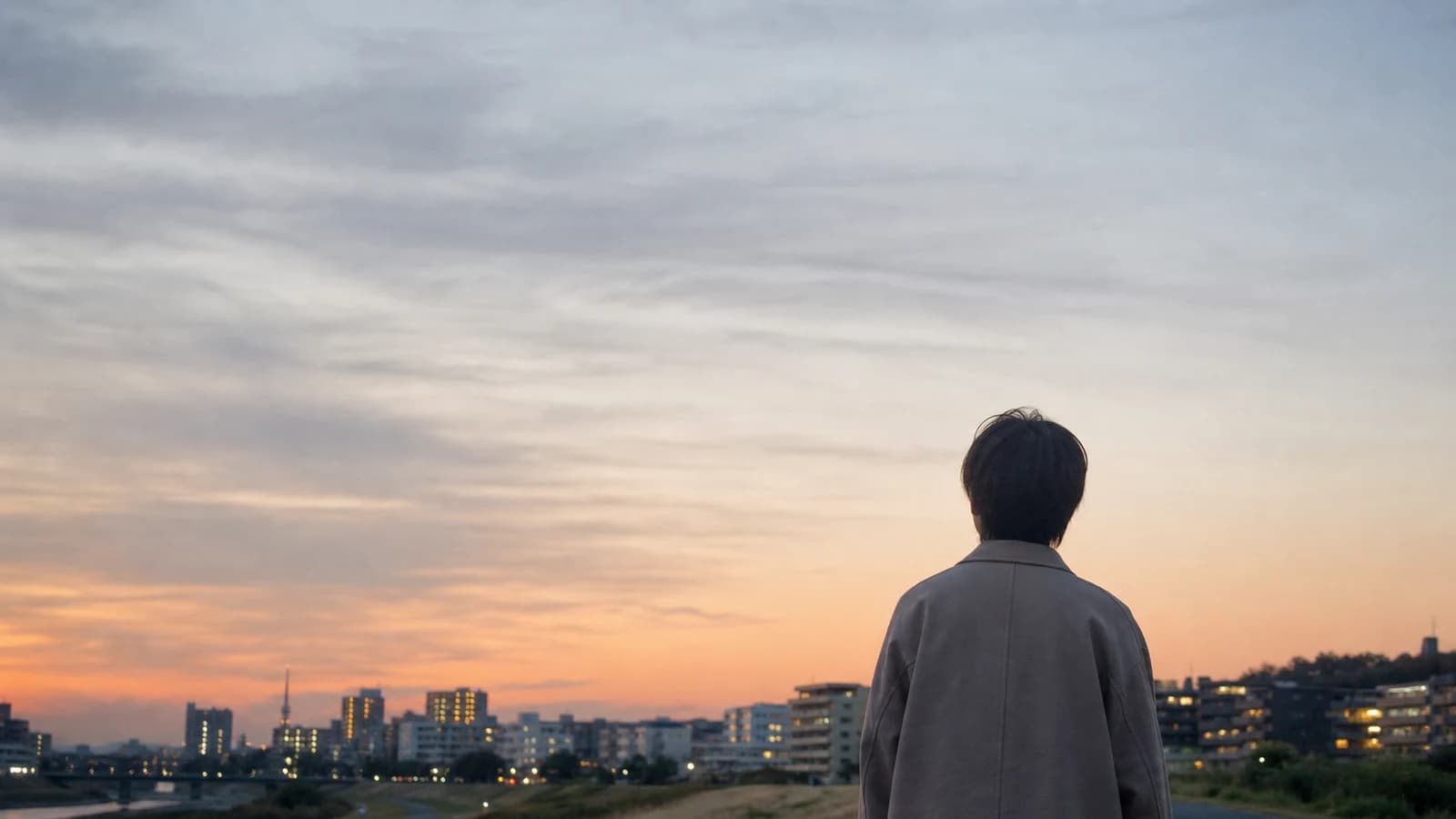 薄明の空を見上げる人の後ろ姿