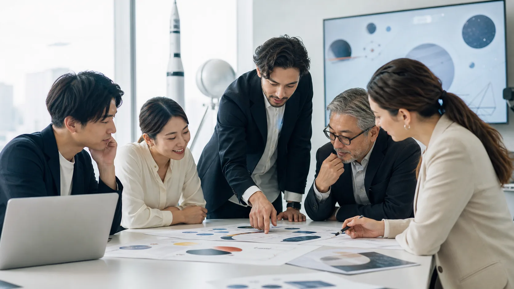 オフィスで多様なメンバーが資料を囲んで議論する、宇宙関連企業のビジネスチームの写真